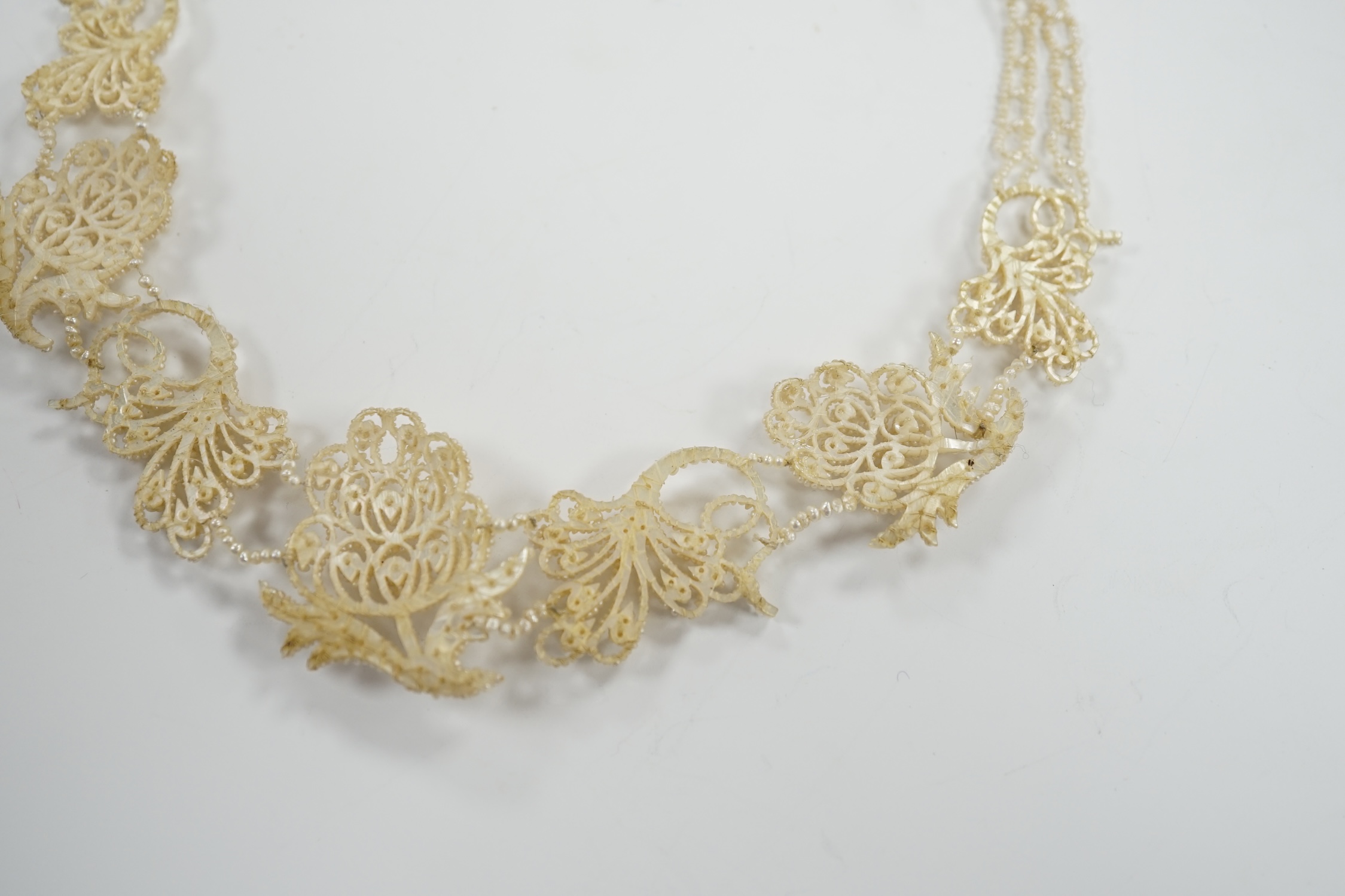 A cased Regency twin strand seed pearl choker necklace with scrolling floral motifs and yellow metal clasp, 34cm.